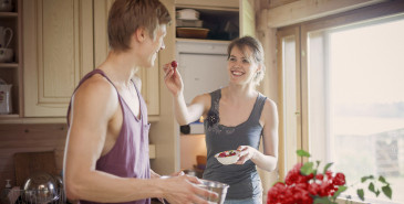 Couple sharing fruit in kitchen