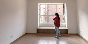 Person standing in empty room looking out window