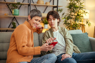 Woman and boy sitting on a couch looking at smartphone 