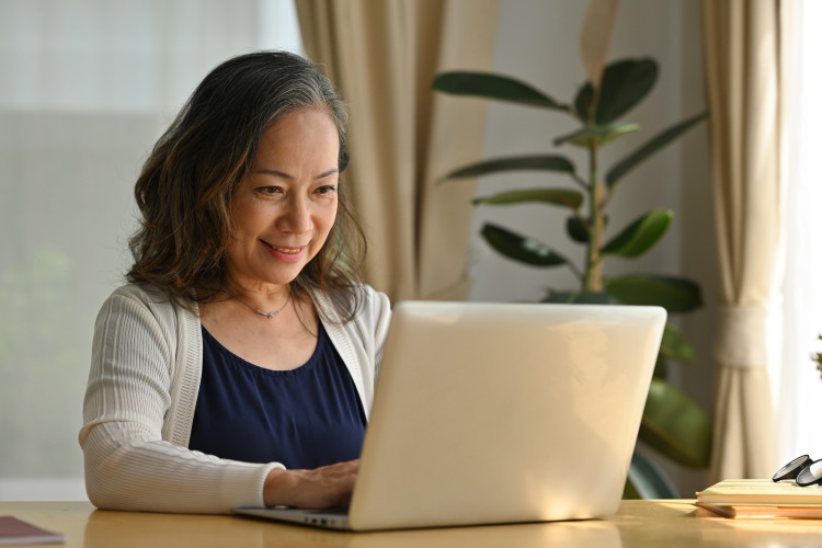 Older Asian woman working at laptop