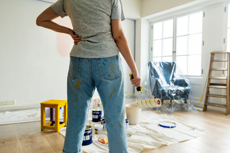 Woman with paint roller looking at room to be painted