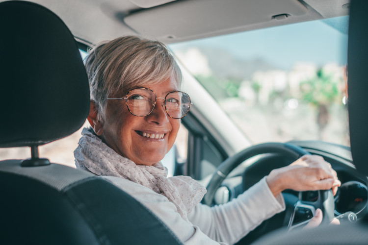 older woman in driver's seat of car looking back at passenger